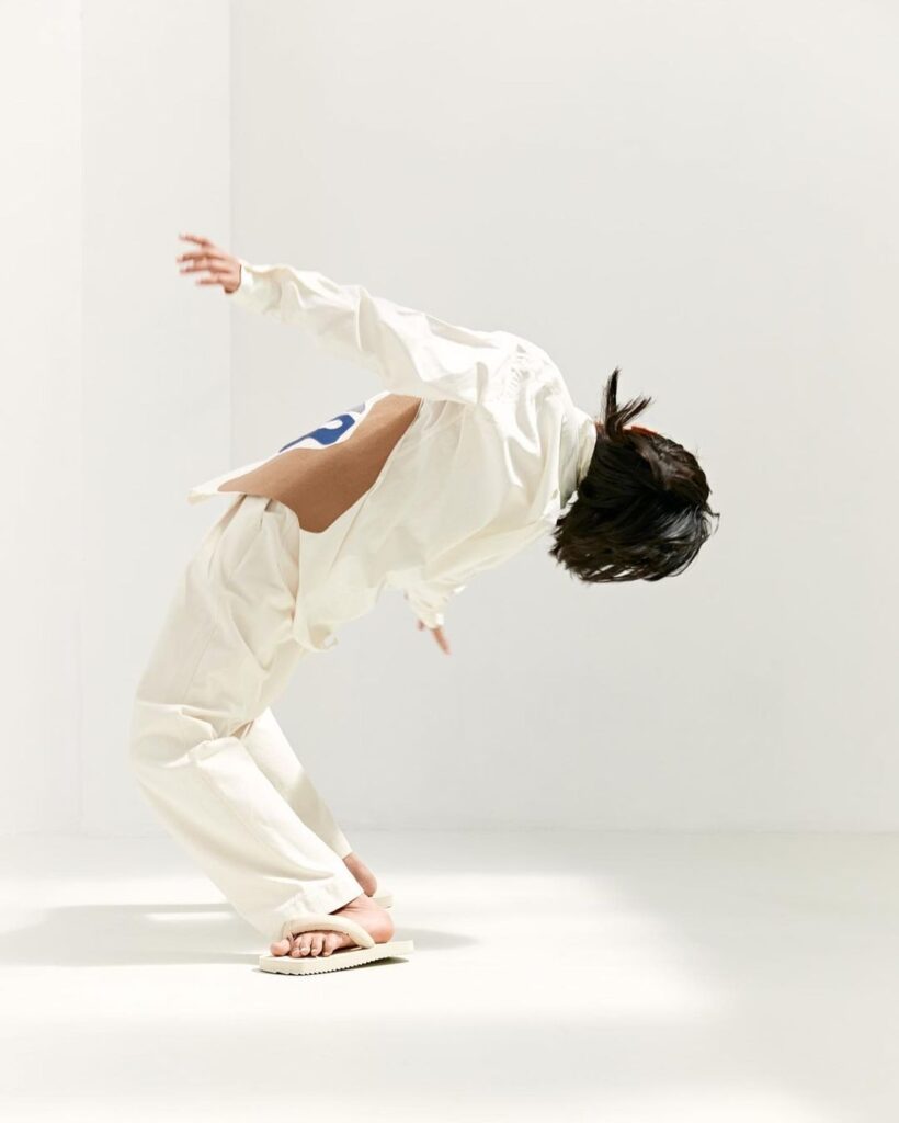 In studio picture of a model in movement, wearing Martan white trousers and printed shirt. 